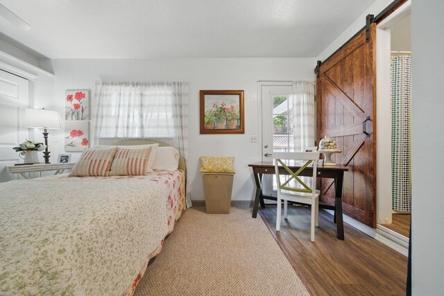 6966 Granada Dr, Redding, CA 96002 - bedroom with a barn door, wood finished floors, and baseboards