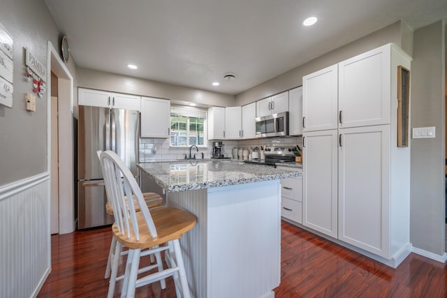 37255 Carson St, Burney, CA 96013 - kitchen with stainless steel appliances, a sink, dark wood-style flooring, a kitchen bar, and decorative backsplash
