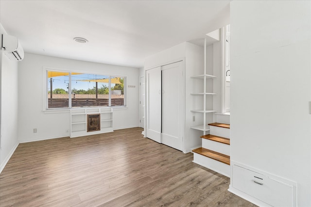 2005 E St, Redding, CA 96001 - unfurnished living room with a wall mounted AC and light wood-style flooring