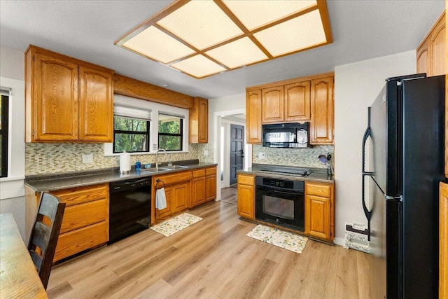 4400 Allen St, Dunsmuir, CA 96025 - kitchen featuring black appliances, a sink, light wood finished floors, tasteful backsplash, and dark countertops