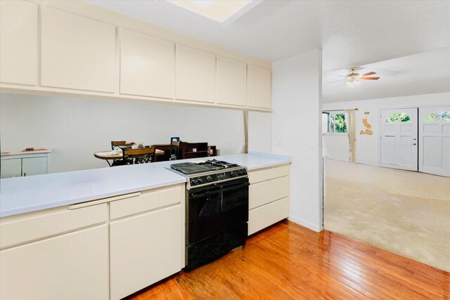 30821 Bambi Dr, Shingletown, CA 96088 - kitchen featuring black gas range oven, light countertops, light wood-style flooring, and white cabinets