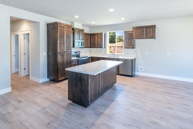 3707 Bloomsbury Ave, Shasta Lake, CA 96019 - kitchen featuring stainless steel appliances, light wood-style flooring, light countertops, a kitchen island, and dark brown cabinets