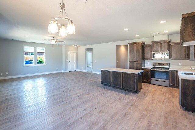 3707 Bloomsbury Ave, Shasta Lake, CA 96019 - kitchen with stainless steel electric range oven, white microwave, a center island, dark brown cabinets, and light countertops