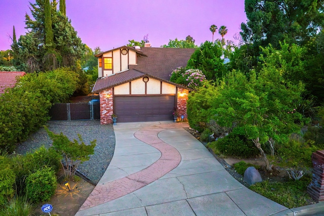 2173 Oak Ridge Dr, Redding, CA 96001 - tudor home with concrete driveway, a chimney, a garage, stucco siding, and brick siding