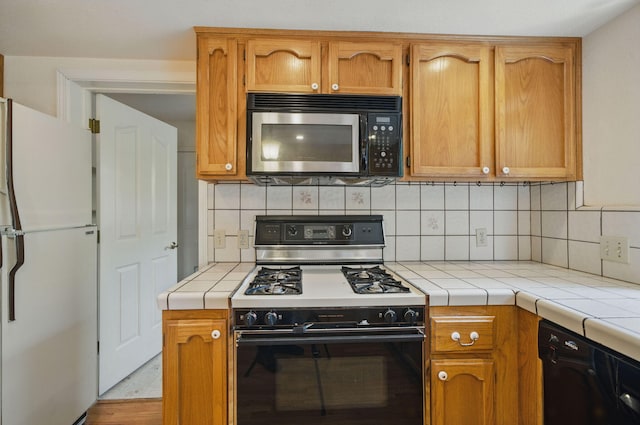 2173 Oak Ridge Dr, Redding, CA 96001 - kitchen with freestanding refrigerator, gas range, tile counters, dishwasher, and tasteful backsplash