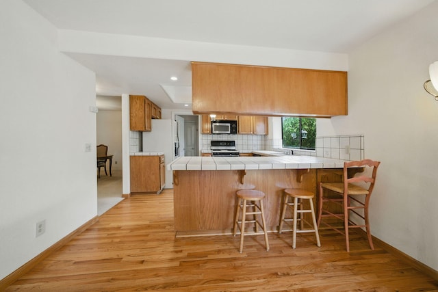 2173 Oak Ridge Dr, Redding, CA 96001 - kitchen featuring stainless steel microwave, range, brown cabinets, light wood-style flooring, and recessed lighting