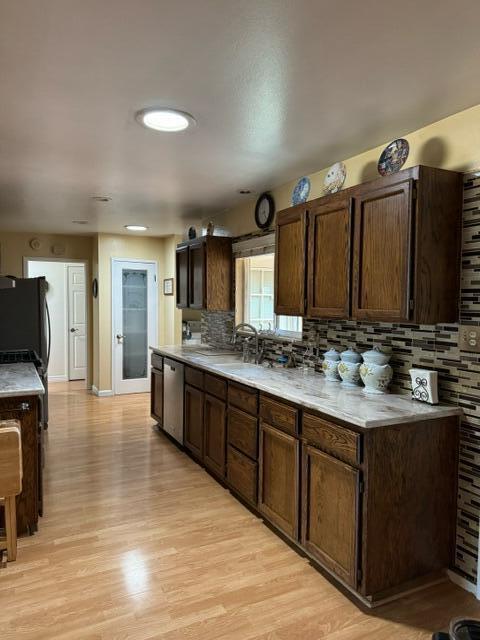 37023 Park Ave, Burney, CA 96013 - kitchen with stainless steel dishwasher, tasteful backsplash, light countertops, and light wood-style flooring