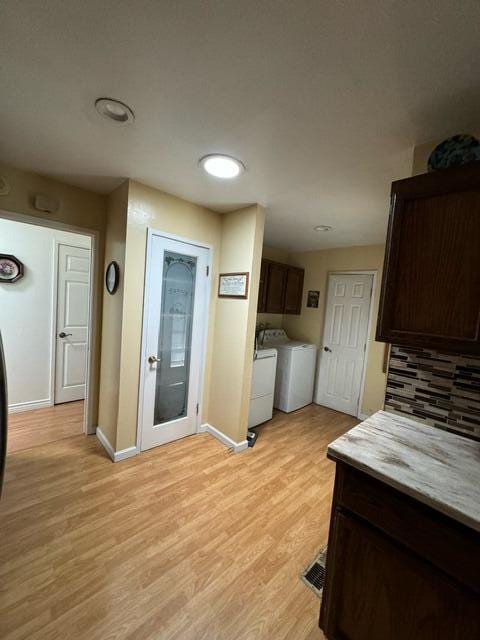 37023 Park Ave, Burney, CA 96013 - kitchen featuring washer and clothes dryer, light wood finished floors, dark brown cabinets, backsplash, and light countertops