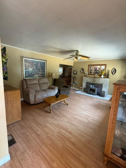 37023 Park Ave, Burney, CA 96013 - living area with a fireplace with raised hearth, wood finished floors, and ceiling fan