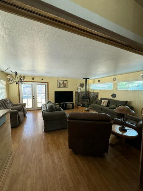 37023 Park Ave, Burney, CA 96013 - living area featuring a wood stove, wood finished floors, a chandelier, french doors, and a textured ceiling