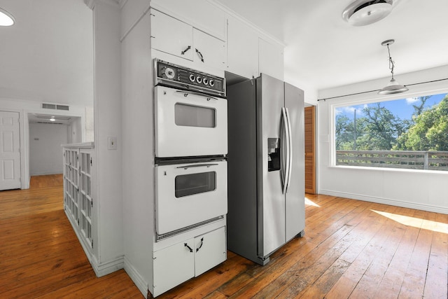 2955 Shasta St, Redding, CA 96001 - kitchen featuring stainless steel fridge, double oven, dark wood-style flooring, and white cabinetry