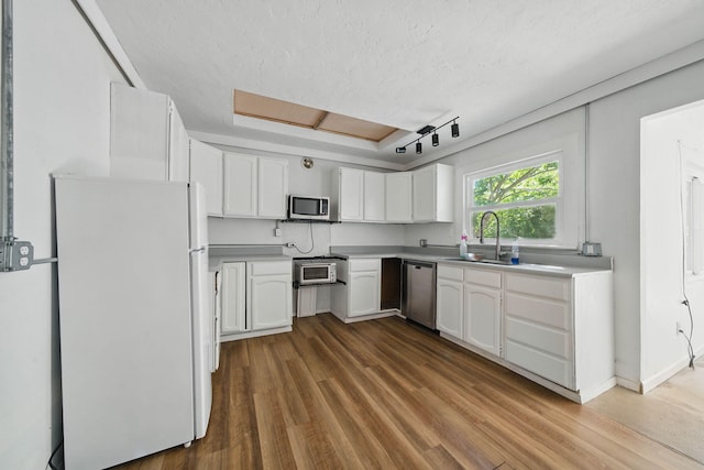 2122 Grape Ave, Redding, CA 96001 - kitchen with appliances with stainless steel finishes, a textured ceiling, wood finished floors, white cabinetry, and light countertops
