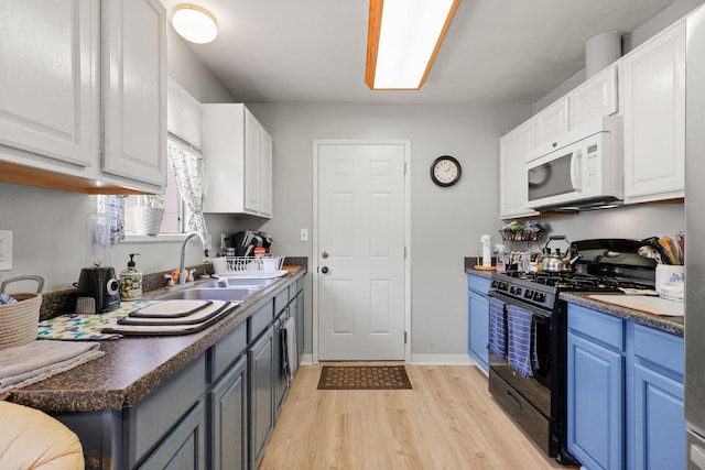 3921 Mercury Dr, Redding, CA 96002 - kitchen with white microwave, black gas range oven, light wood finished floors, and white cabinetry