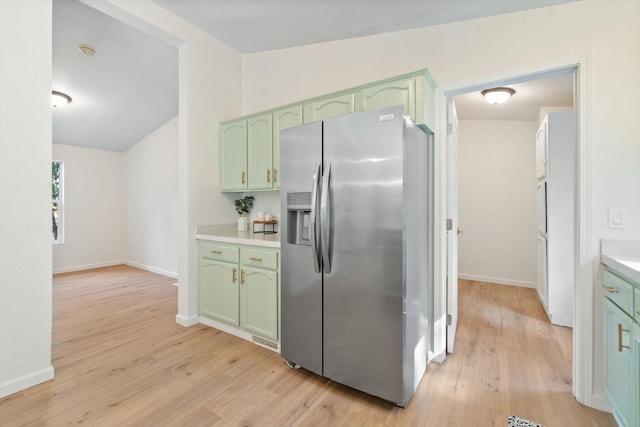 7727 Pegnan Rd, Shingletown, CA 96088 - kitchen with green cabinetry, stainless steel refrigerator with ice dispenser, light countertops, light wood-style flooring, and vaulted ceiling