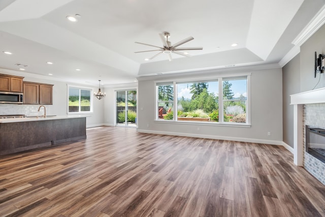 4537 Risstay Way, Shasta Lake, CA 96019 - unfurnished living room featuring a glass covered fireplace, ornamental molding, a ceiling fan, a chandelier, and a raised ceiling