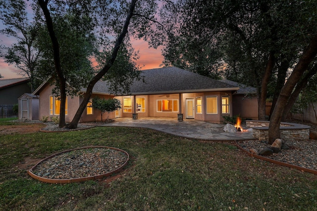 4230 Brittany Dr, Redding, CA 96002 - back of property at dusk featuring an outdoor fire pit, a patio, a shed, and stucco siding