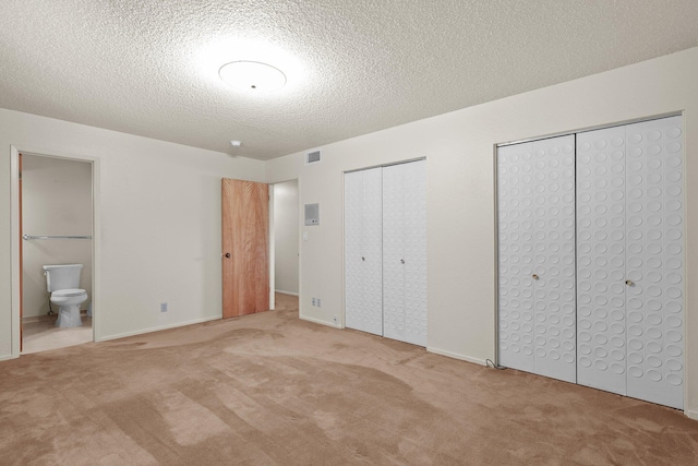 910 Hallmark Dr, Redding, CA 96001 - unfurnished bedroom featuring carpet floors, two closets, a textured ceiling, and ensuite bath