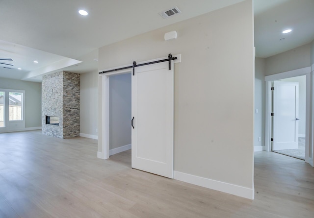 19450 Vista Del Monte Ct, Redding, CA 96003 - unfurnished living room with light wood-style floors, a barn door, recessed lighting, a stone fireplace, and ceiling fan