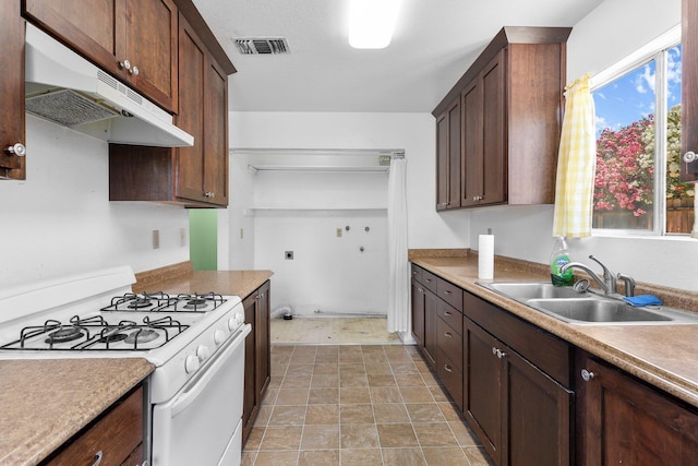 1333 Deborah Dr, Red Bluff, CA 96080 - kitchen with white range with gas cooktop, under cabinet range hood, dark brown cabinets, light countertops, and light stone finish flooring