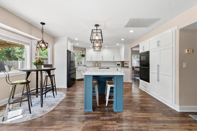4676 Dandelion Dr, Redding, CA 96002 - kitchen with black appliances, a center island, white cabinetry, light countertops, and a kitchen bar