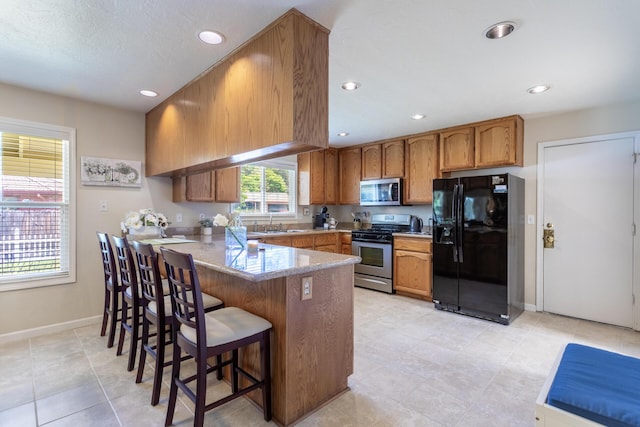 676 Country Oak Dr, Redding, CA 96003 - kitchen with stainless steel appliances, a peninsula, brown cabinets, recessed lighting, and a breakfast bar