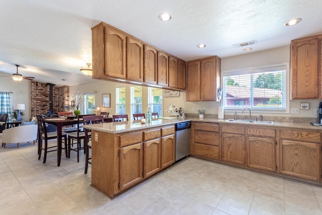676 Country Oak Dr, Redding, CA 96003 - kitchen featuring a wood stove, stainless steel dishwasher, brown cabinets, recessed lighting, and a textured ceiling