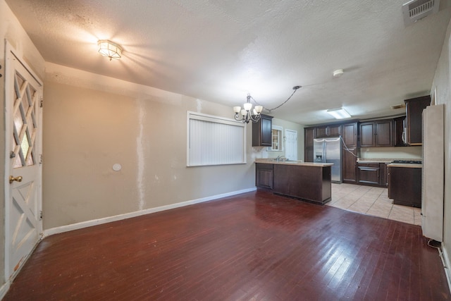 1440 Oakdale Ln, Redding, CA 96002 - kitchen with a chandelier, stainless steel fridge, light wood-style flooring, a peninsula, and light countertops