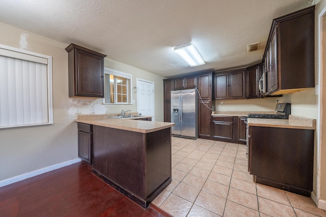 1440 Oakdale Ln, Redding, CA 96002 - kitchen with stainless steel fridge with ice dispenser, dark brown cabinets, light countertops, a peninsula, and gas stove
