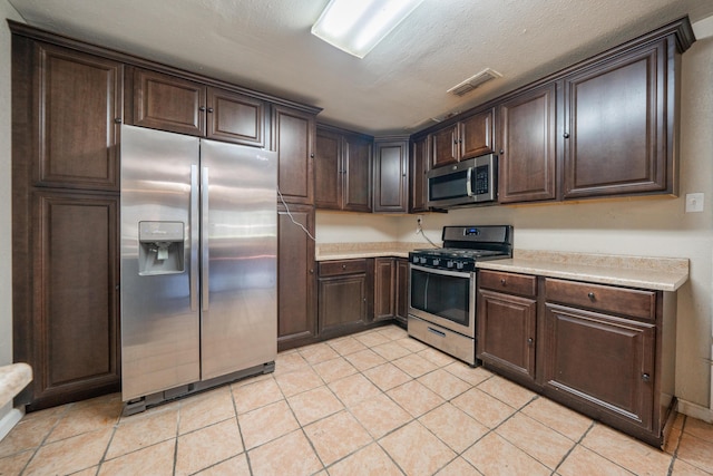 1440 Oakdale Ln, Redding, CA 96002 - kitchen with stainless steel appliances, light countertops, dark brown cabinetry, and light tile patterned flooring