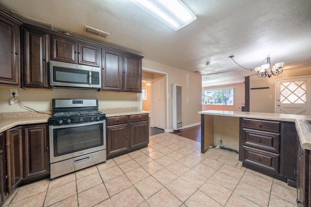 1440 Oakdale Ln, Redding, CA 96002 - kitchen featuring appliances with stainless steel finishes, light countertops, dark brown cabinetry, and a textured ceiling