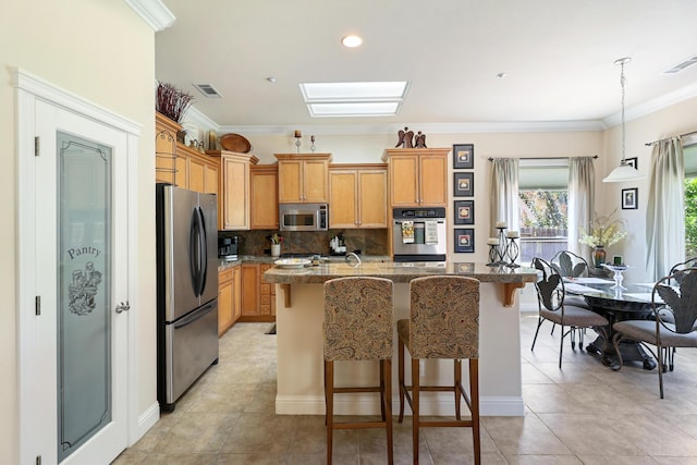 1835 Dellwood Dr, Redding, CA 96003 - kitchen with appliances with stainless steel finishes, a kitchen island with sink, backsplash, a kitchen bar, and light tile patterned floors