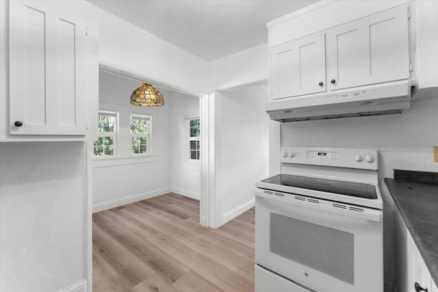 830 W St, Redding, CA 96001 - kitchen featuring white electric range oven, under cabinet range hood, light wood finished floors, white cabinetry, and dark countertops