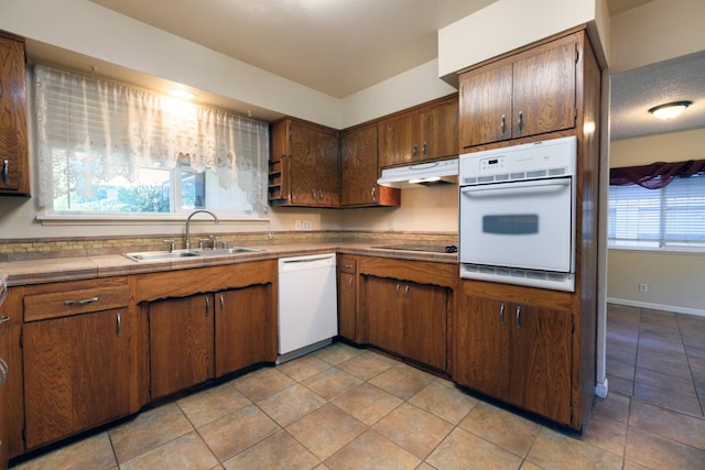 6781 Reflection St, Redding, CA 96001 - kitchen with white appliances, under cabinet range hood, light tile patterned floors, and tile countertops