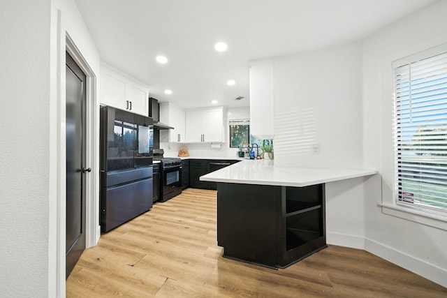 1683 Lakeside Dr, Redding, CA 96001 - kitchen with freestanding refrigerator, black gas stove, wall chimney range hood, a peninsula, and white cabinetry