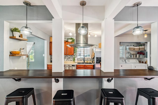 2623 Freebridge St, Redding, CA 96001 - bar area featuring appliances with stainless steel finishes, decorative backsplash, washing machine and clothes dryer, and pendant lighting