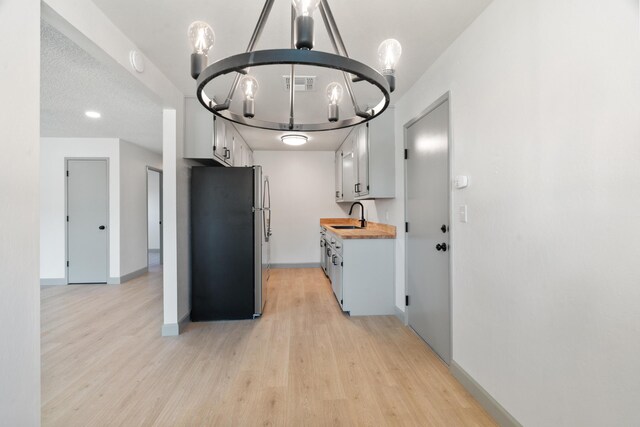 3704 Polaris Way, Redding, CA 96002 - kitchen featuring freestanding refrigerator, a chandelier, light wood-style floors, white cabinetry, and butcher block counters