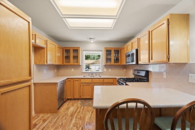4592 Impression Way, Shasta Lake, CA 96019 - kitchen featuring appliances with stainless steel finishes, a peninsula, light wood-style floors, a kitchen breakfast bar, and glass insert cabinets