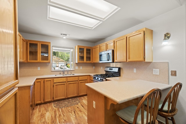 4592 Impression Way, Shasta Lake, CA 96019 - kitchen featuring stainless steel appliances, a peninsula, light wood-style flooring, backsplash, and glass insert cabinets