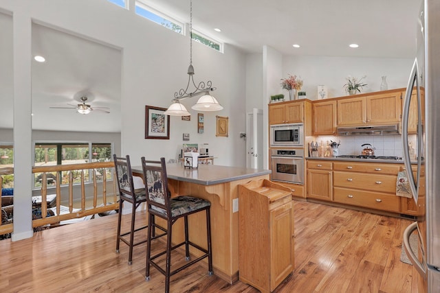 6949 Rector Creek Rd, Igo, CA 96047 - kitchen with stainless steel appliances, high vaulted ceiling, under cabinet range hood, backsplash, and a breakfast bar area