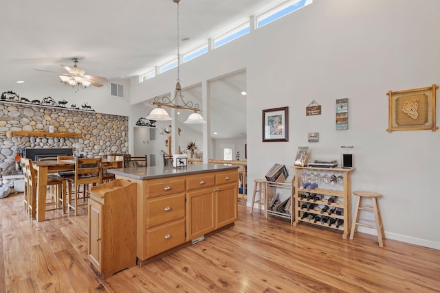 6949 Rector Creek Rd, Igo, CA 96047 - kitchen with a ceiling fan, light wood-style flooring, a towering ceiling, a kitchen island, and a fireplace