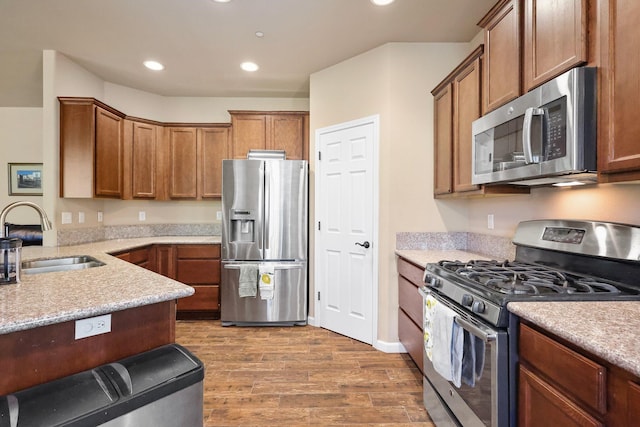 3526 Humbug Dr, Anderson, CA 96007 - kitchen featuring appliances with stainless steel finishes, wood finished floors, recessed lighting, brown cabinetry, and a peninsula