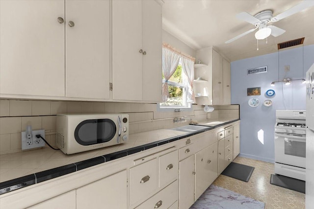 1120 Franklin St, Red Bluff, CA 96080 - kitchen featuring white gas stove, tile counters, tasteful backsplash, a ceiling fan, and white cabinetry