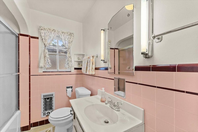 1120 Franklin St, Red Bluff, CA 96080 - bathroom featuring heating unit, vanity, tile walls, wainscoting, and combined bath / shower with glass door