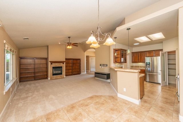 2926 Chaucer Way, Shasta Lake, CA 96019 - kitchen with stainless steel fridge with ice dispenser, brown cabinets, light countertops, a peninsula, and a glass covered fireplace