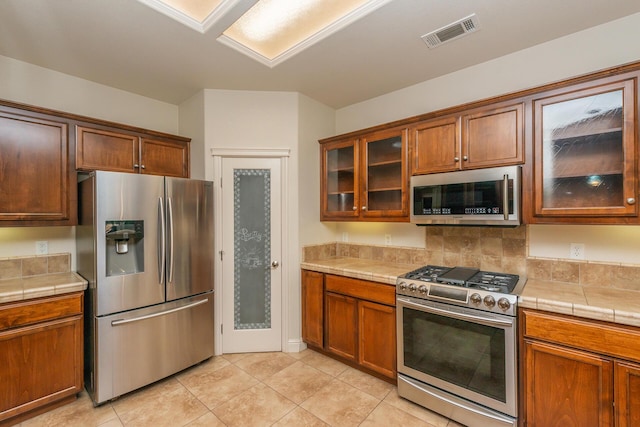 2926 Chaucer Way, Shasta Lake, CA 96019 - kitchen featuring stainless steel appliances, tile counters, light tile patterned flooring, and glass insert cabinets