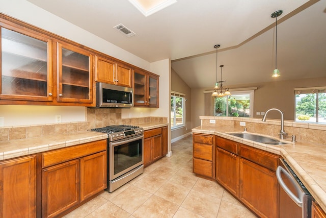 2926 Chaucer Way, Shasta Lake, CA 96019 - kitchen with stainless steel appliances, brown cabinetry, decorative backsplash, light tile patterned flooring, and decorative light fixtures