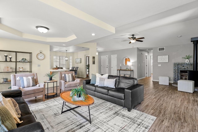 2820 Howard Dr, Redding, CA 96001 - living area with a wood stove, ceiling fan, wood finished floors, and a raised ceiling