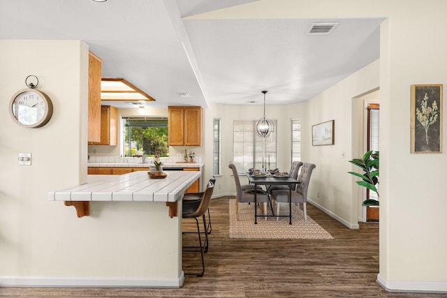 2820 Howard Dr, Redding, CA 96001 - kitchen with tile counters, a kitchen bar, dark wood-style floors, and brown cabinets