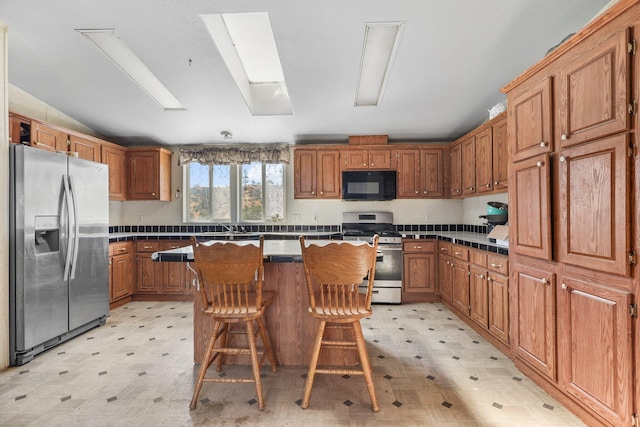3287 Yolla Bolly Rd, Igo, CA 96047 - kitchen with stainless steel appliances, light flooring, a center island, lofted ceiling, and brown cabinetry