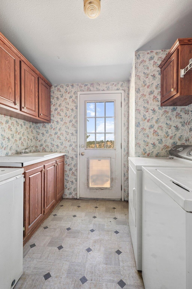 3287 Yolla Bolly Rd, Igo, CA 96047 - laundry room with washing machine and clothes dryer, cabinet space, wallpapered walls, light floors, and a textured ceiling